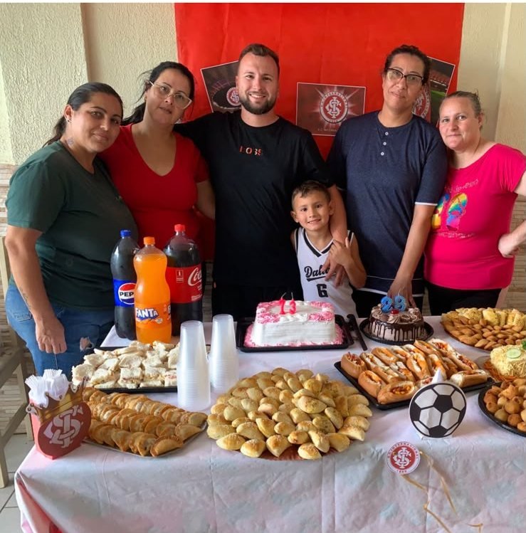Equipe do Lar de Idosos Renan reunida com Renan e seu filho durante uma comemoração